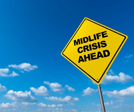 Vor einem strahlend blauen Himmel steht ein gelbes Verkehrsschild mit dem Text "Midlife Crisis Ahead"