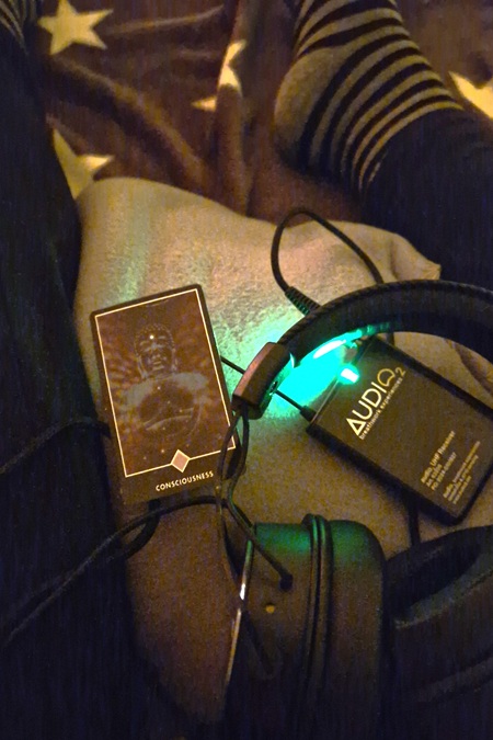 Auf einer Decke liegen Kopfhörer, ein Sender und eine gezogene Tarot-Karte