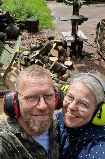 Tina und ihr Partner vor einem Berg von Brennholz für den kommenden Winter