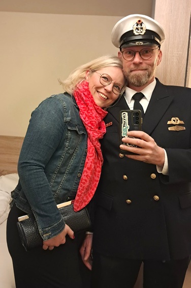 Tina und ihr Partner sind fein gekleidet und machen ein Selfie vor dem Spiegel im Vorfeld einer Hochzeit