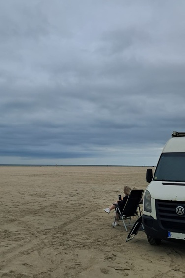 Unser Wohnmobil am Strand, vor dem Wohnmobil sitzt Tina im Klappstuhl