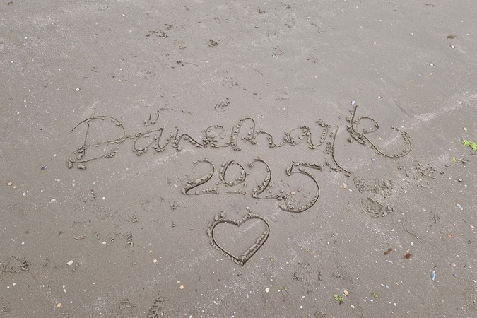 ein Lettering im Sand am Strand mit den Worten "Dänemark 2025" und einem Herz