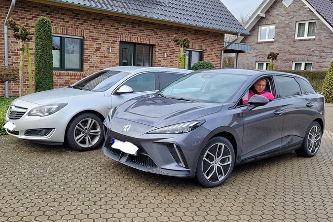 Das neue E-Auto vor dem alten Verbrenner-Auto. Tina sitzt im vorderen E-Auto