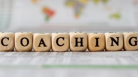 Auf kleinen Holzwürfeln stehen einzelne Buchstaben. Insgesamt ergibt sich das Wort "Coaching".